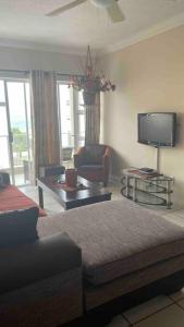 Una sala de estar con un sofá y un televisor en Cerf@BeachFront, en Margate