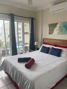 1 dormitorio con 1 cama blanca grande con almohadas azules y rojas en Cerf@BeachFront, en Margate