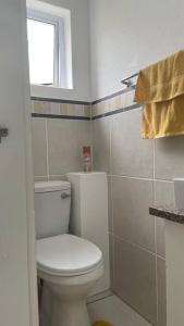 Un baño con inodoro blanco y ventana. en Cerf@BeachFront, en Margate