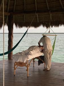 a man is making a bed on a dock at Xoot Ka’Ana villa fantasía in Bacalar