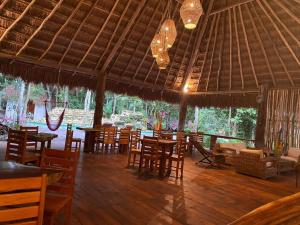 a restaurant with wooden tables and chairs and chandeliers at Xoot Ka’Ana villa fantasía in Bacalar