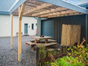 a picnic table under a pergola next to a building at Atmospheric Holiday Home in B llingen with Infrared Sauna in Bullange