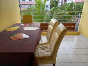 a table and chairs with a table and a balcony at Magnifique T2 meublé avec piscine in Cayenne
