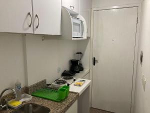 une cuisine avec un évier, une cuisinière et un micro-ondes dans l'établissement 104 Apart mobiliado vista mar Praia de Iracema, à Fortaleza