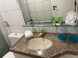 une salle de bain avec un lavabo, des toilettes et un miroir dans l'établissement 104 Apart mobiliado vista mar Praia de Iracema, à Fortaleza