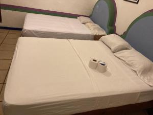 due letti con lenzuola bianche e due tazze sopra di Pargos Hotel & Cowork a Puerto Escondido