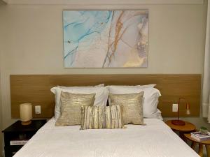 - une chambre dotée d'un lit blanc avec des oreillers et un tableau dans l'établissement Apartment Ipanema Arpoador - 300m da praia, à Rio de Janeiro