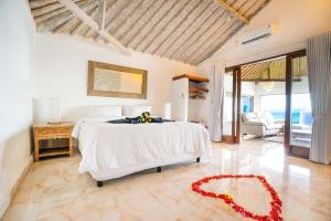 a bedroom with a white bed with a red flower on the floor at Bali Secrets Retreat in Candidasa +73 photos