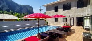a swimming pool with chairs and umbrellas next to a building at Aonang Lodge - SHA in Ao Nang Beach