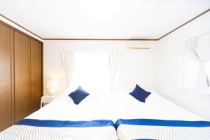 a bedroom with a white bed with blue pillows at Awaji Garden House in Shinmura in Sumoto +45 photos