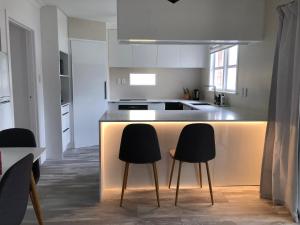 a kitchen with a counter with three chairs at it at Comfortable Holiday Home at Mt Wellington in Auckland