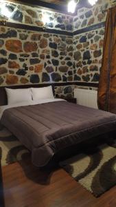 a bed in a room with a stone wall at Xenonas Pantheon in Palaios Agios Athanasios