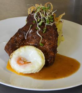 a plate of food with a fried egg and sauce at Hotel Lužnice in Planá nad Lužnicí
