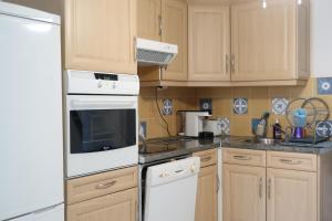 a kitchen with white appliances and wooden cabinets at Maison à la plage climatisée et wifi fibre pour télétravail in Saint-Cyprien