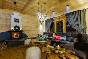 a living room with a couch and a fireplace at Bajkowa Chata 3 Magiczne Domki Jacuzzi in Murzasichle