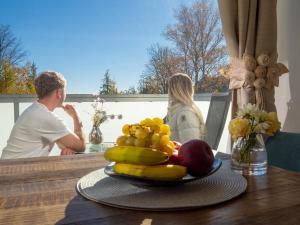 a man and woman sitting at a table with a plate of fruit at Cozy Studio with NETFLIX - Apartmanovy dom Bernard in Nový Smokovec