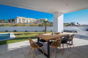 einen Holztisch und Stühle auf einer Terrasse mit Aussicht in der Unterkunft Villa moderne proche de la mer in Manilva