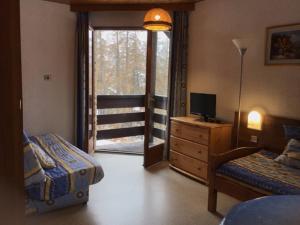 um quarto com uma cama, uma televisão e uma janela em Chalet les arolles em Les Orres