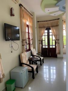 a living room with two chairs and a flat screen tv at Anh Nguyen Guesthouse in Pleiku