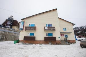 a house with a building and a snow covered ground at Voyage Hotel in Sheregesh