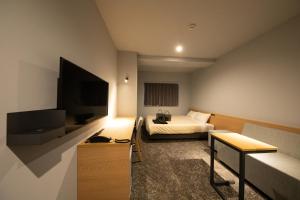 a hotel room with a bed and a flat screen tv at AMANEK Inn Beppu in Beppu