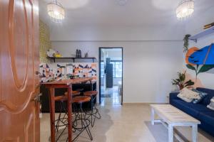 a living room with a table and a blue couch at La Casa - Stunning 1BHK Apartment - Vagator, Goa By StayMonkey in Vagator