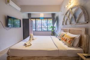 um quarto com uma cama grande e uma janela em La Casa - Stunning 1BHK Apartment - Vagator, Goa By StayMonkey em Vagator