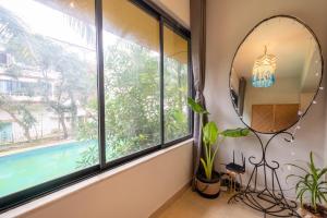 a mirror and a plant in a room with windows at La Casa - Stunning 1BHK Apartment - Vagator, Goa By StayMonkey in Vagator