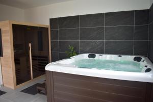 uma banheira na casa de banho com azulejos pretos em Château de Montabert em Montaulin