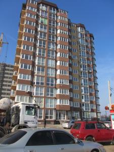 un edificio alto con auto parcheggiate in un parcheggio di Уютная 1 комнатная квартира ЗИМНЯЯ ВИШНЯ в ж/к Новая Европа a Korsuntsy