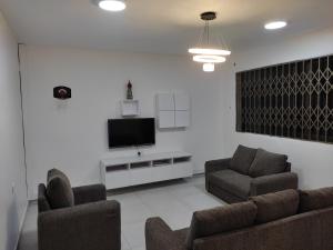 La Casa Maite - Stunning Studio Apartment في Botianaw: غرفة معيشة مع كرسيين وتلفزيون بشاشة مسطحة