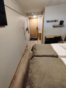 Cette chambre comprend deux lits et un bureau. dans l'établissement Hotelli Toivola, à Kemi