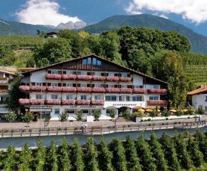 un hotel con un río frente a una montaña en Hotel Schennerhof, en Scena