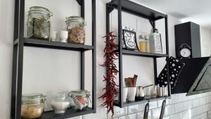 a kitchen with two black shelves with food items at Apartman H8 in Bjelovar
