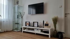 a living room with a white shelf with a television on a wall at Apartman H8 in Bjelovar