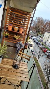 a balcony with a wooden bench and potted plants at Apartman H8 in Bjelovar