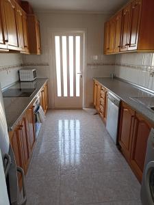 una cocina con armarios de madera y una gran ventana en L'Apostille, en Mazarrón