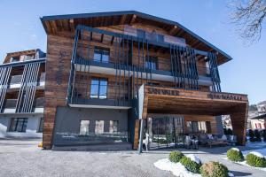 un grand bâtiment avec une façade en bois dans l'établissement Hotel San Valier, à Cavalese