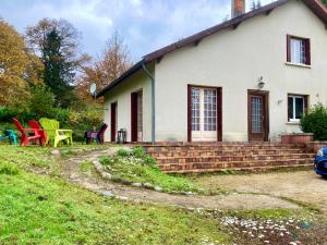 a white house with a yard with colorful chairs at Appartement La Marmotte Compreignac in Compreignac