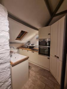 a kitchen with white cabinets and a stove top oven at Two Bedroom Barn Conversion in Newquay