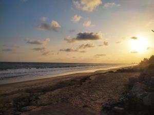 a beach with the sun setting over the ocean at La Casa Maite - Stunning Studio Apartment in Bortianor