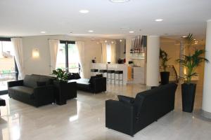 a living room with black furniture and a kitchen at Hotel San Rocco in Muggia