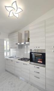 cocina con armarios blancos y fogones en Villa Miami en Bibione