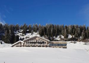 un edificio en la cima de una montaña cubierta de nieve en AUBERGE DES GLIERES en Thorens-Glières