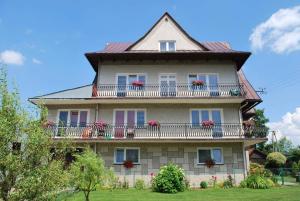 un gran edificio con balcones y flores. en Agroturystyka u Marty en Tylicz