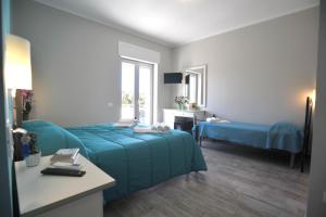 1 dormitorio con cama azul, escritorio y ventana en Agriturismo San Raphael, en Capaccio-Paestum