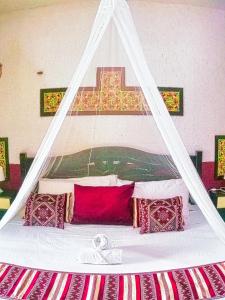 un letto bianco con cuscini rossi e una croce sopra di esso di Beachfront Apartment Hacienda del Cuyo a El Cuyo