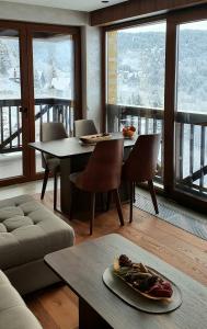 a living room with a table and chairs and windows at Vista47 Zoned II Kopaonik in Kopaonik