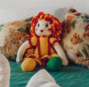 a small crochet doll sitting on a bed at Chalés Tia Nastácia in Monteiro Lobato