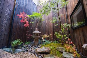 a garden in front of a fence with a lantern at 櫛笥ノ家 Machiya Kushige in Kyoto +54 photos